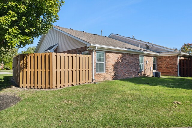 back of property featuring central air condition unit and a yard