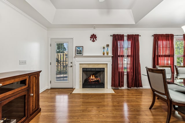 living room featuring ornamental molding, a high end fireplace, hardwood / wood-style flooring, and a raised ceiling