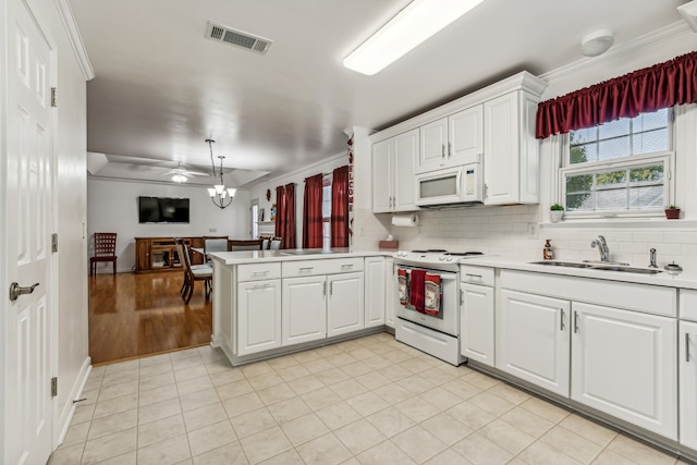 kitchen with white appliances, sink, kitchen peninsula, and white cabinets