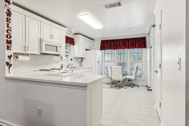 kitchen with white cabinetry, kitchen peninsula, white appliances, and tasteful backsplash