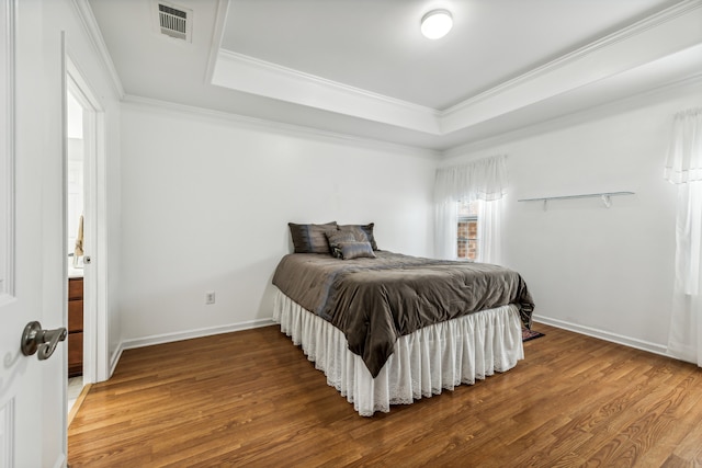 bedroom featuring hardwood / wood-style flooring, ornamental molding, and a tray ceiling