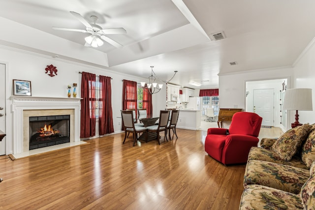 living room featuring ornamental molding, hardwood / wood-style floors, and ceiling fan with notable chandelier