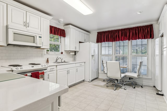 kitchen with backsplash, sink, light tile patterned floors, white cabinets, and white appliances