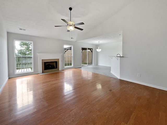 unfurnished living room with ceiling fan, hardwood / wood-style flooring, a textured ceiling, and lofted ceiling