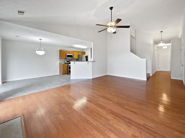 unfurnished living room with dark hardwood / wood-style floors, high vaulted ceiling, and ceiling fan with notable chandelier