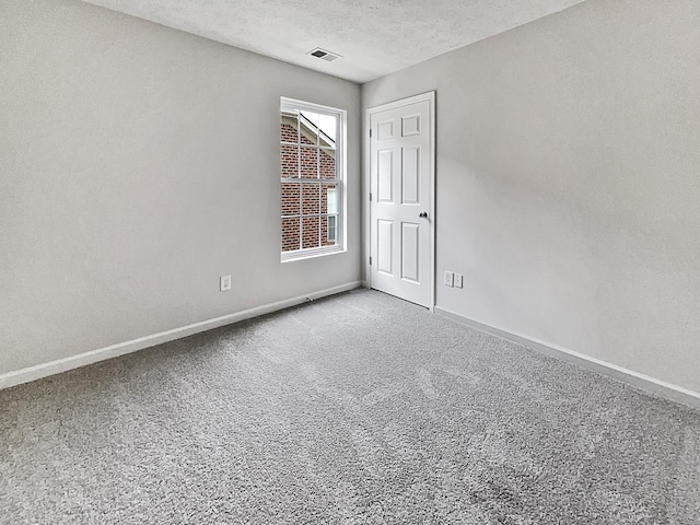 carpeted empty room featuring a textured ceiling