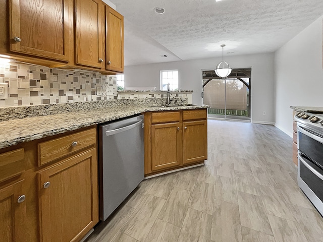 kitchen with decorative backsplash, hanging light fixtures, appliances with stainless steel finishes, light stone countertops, and sink