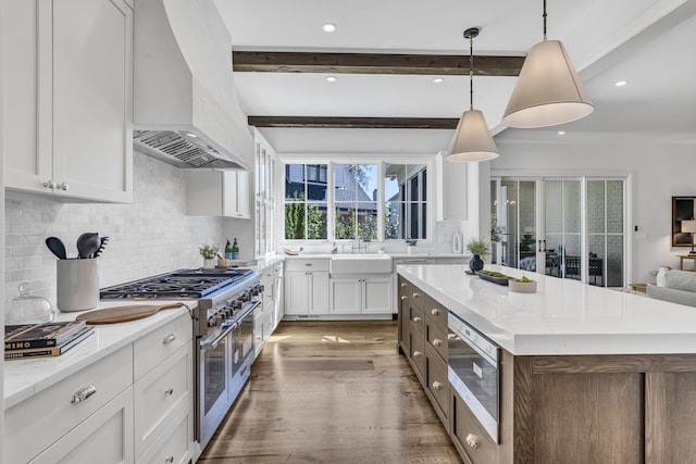 kitchen with beamed ceiling, range with two ovens, pendant lighting, custom exhaust hood, and white cabinets