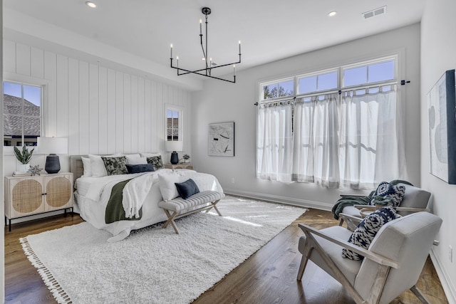 bedroom with dark hardwood / wood-style floors and a chandelier