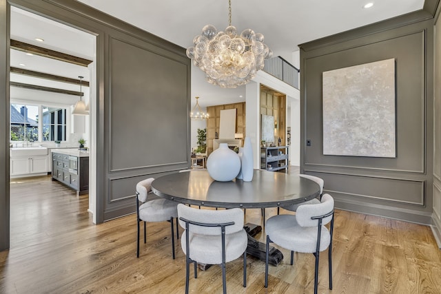 dining space featuring light hardwood / wood-style floors, sink, and an inviting chandelier