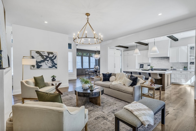 living room featuring beamed ceiling, light hardwood / wood-style flooring, and an inviting chandelier