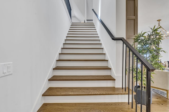 stairs featuring hardwood / wood-style floors and a chandelier