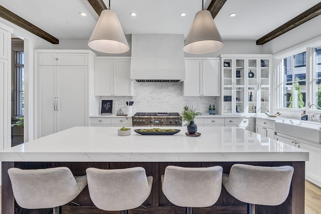 kitchen featuring custom range hood, white cabinetry, and a center island