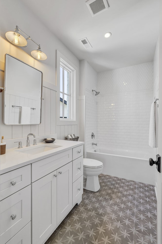 full bathroom featuring vanity, tiled shower / bath combo, and toilet