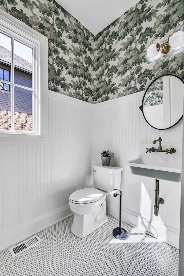 bathroom featuring a wealth of natural light, toilet, and tile patterned flooring