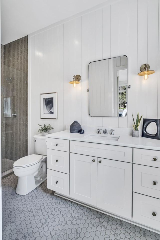 bathroom with toilet, vanity, and a tile shower