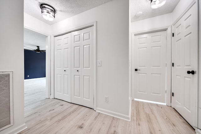 corridor with light hardwood / wood-style flooring and a textured ceiling