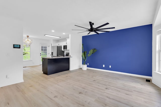 kitchen with light hardwood / wood-style flooring, kitchen peninsula, white cabinetry, appliances with stainless steel finishes, and ceiling fan