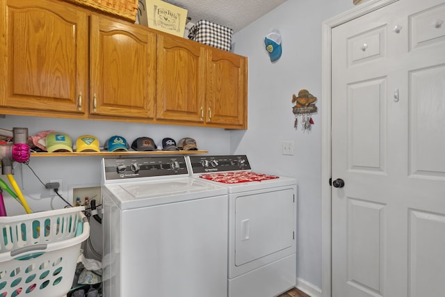 washroom featuring cabinets, a textured ceiling, and washing machine and clothes dryer