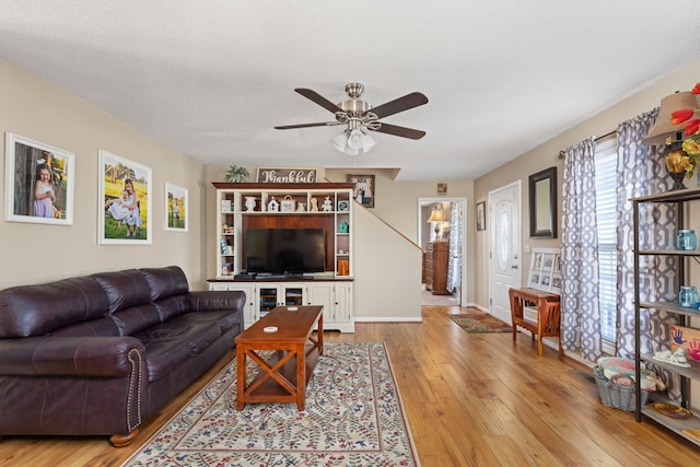 living room featuring ceiling fan, a textured ceiling, and light wood-type flooring