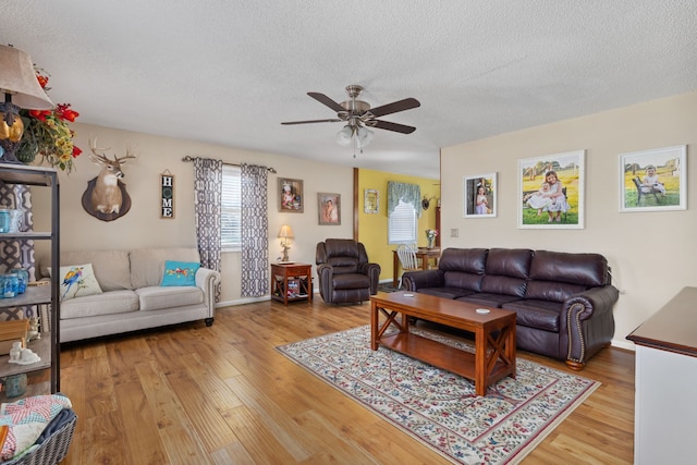 living room with a textured ceiling, wood-type flooring, and ceiling fan