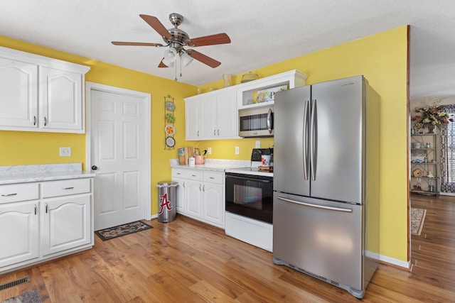 kitchen with white cabinetry, stainless steel appliances, a textured ceiling, and light hardwood / wood-style flooring