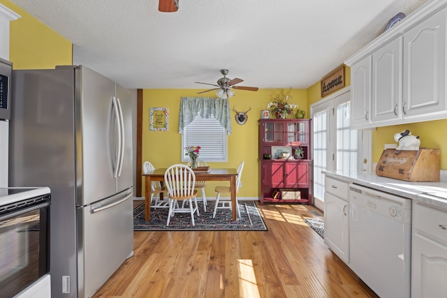 kitchen featuring appliances with stainless steel finishes, a textured ceiling, white cabinetry, ceiling fan, and light hardwood / wood-style flooring