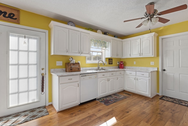 kitchen with light hardwood / wood-style flooring, white dishwasher, sink, white cabinets, and a textured ceiling