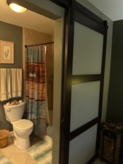 bathroom featuring toilet, shower / bath combo with shower curtain, and tile patterned floors