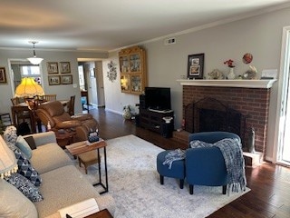 living room with ornamental molding, dark wood-type flooring, and a fireplace