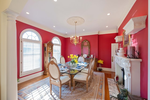 dining space with crown molding, decorative columns, a chandelier, and light wood-type flooring