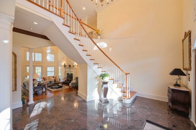 foyer entrance with a towering ceiling, ornamental molding, and decorative columns