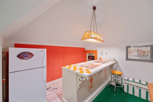 kitchen featuring white fridge, light tile patterned floors, vaulted ceiling, and pendant lighting