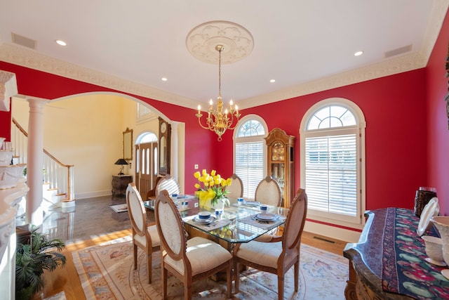 dining area featuring decorative columns, wood-type flooring, and a chandelier