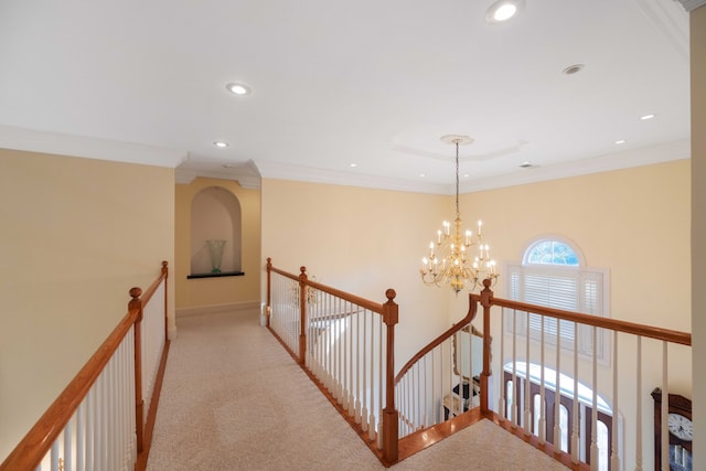 hallway featuring crown molding, a notable chandelier, and light colored carpet