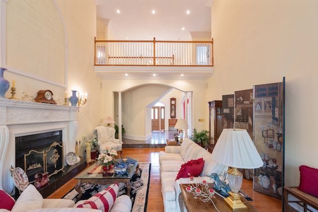 living room featuring a towering ceiling, ornamental molding, and wood-type flooring