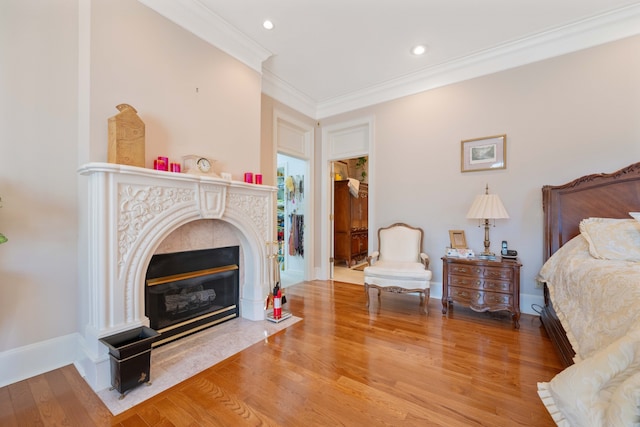 bedroom featuring crown molding, wood-type flooring, and a tile fireplace