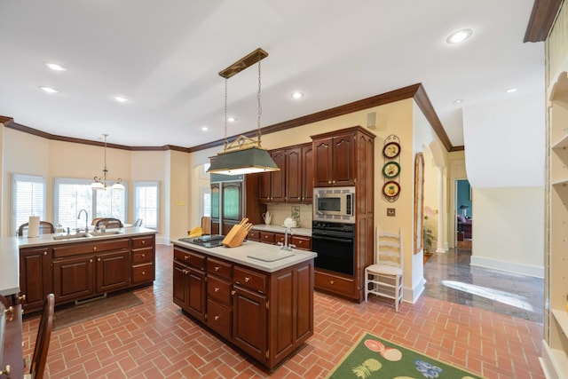 kitchen featuring stainless steel microwave, sink, hanging light fixtures, black oven, and a center island with sink