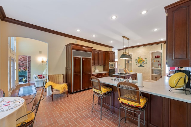 kitchen featuring kitchen peninsula, hanging light fixtures, a breakfast bar area, a wealth of natural light, and built in appliances