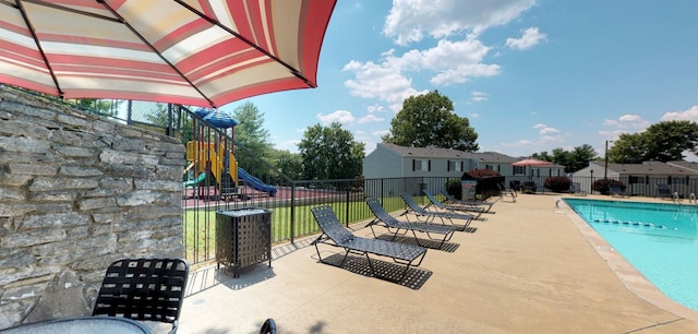 view of swimming pool featuring a water slide, a patio, and a playground