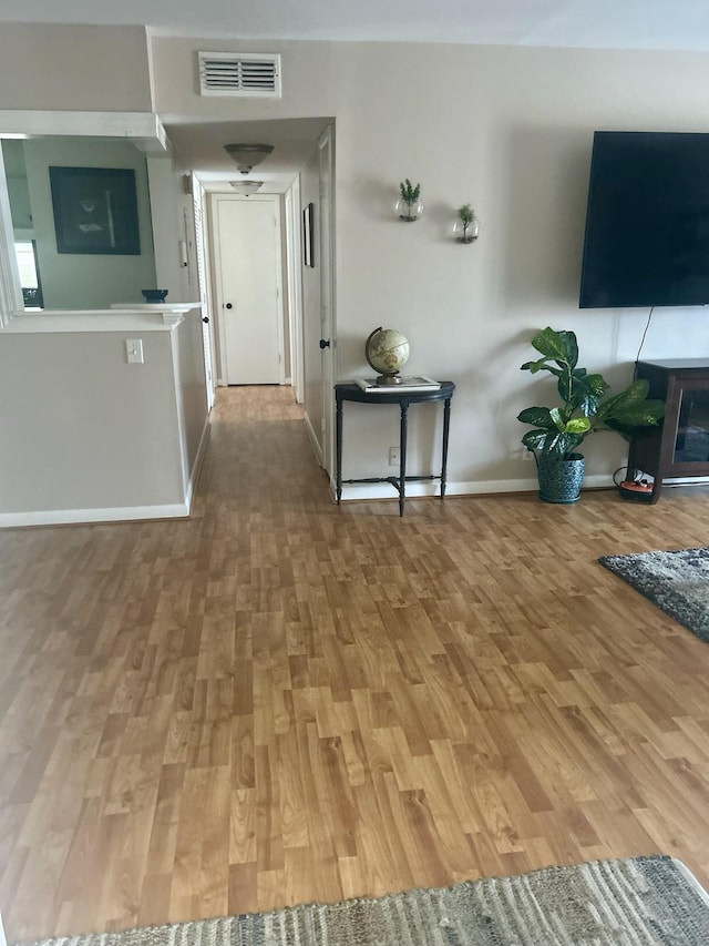 corridor with baseboards, light wood-style flooring, and visible vents