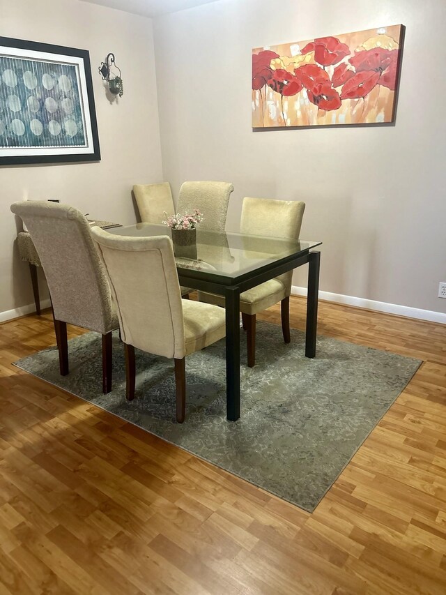 dining space with baseboards and wood finished floors