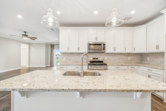 kitchen with appliances with stainless steel finishes, sink, an island with sink, and decorative light fixtures