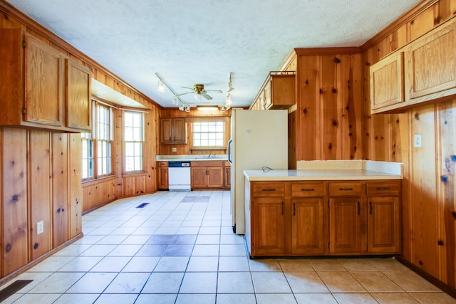 kitchen with wooden walls, crown molding, light tile patterned floors, white appliances, and ceiling fan