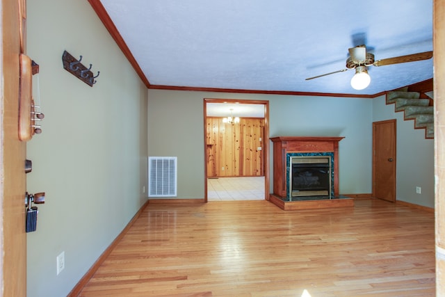 unfurnished living room with crown molding, ceiling fan with notable chandelier, a fireplace, and light wood-type flooring