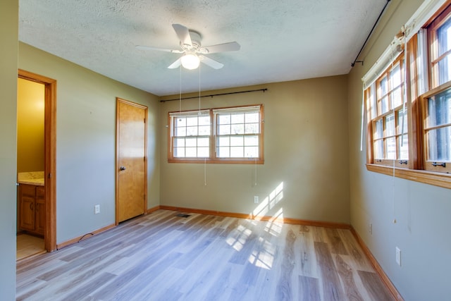 unfurnished bedroom with connected bathroom, light hardwood / wood-style floors, a textured ceiling, and ceiling fan