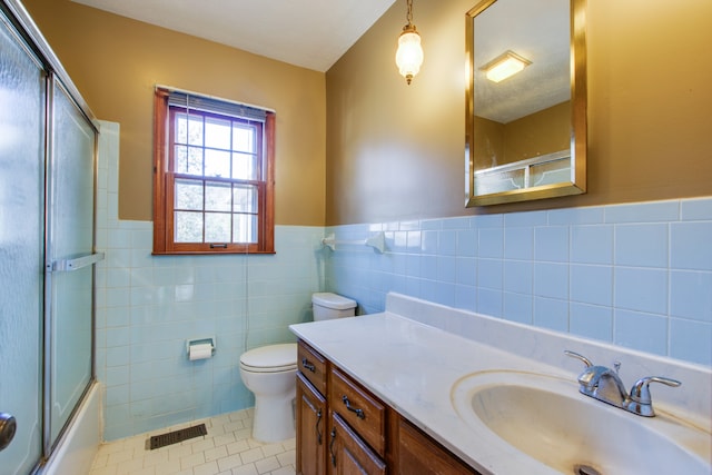 full bathroom with a textured ceiling, tile walls, toilet, vanity, and tile patterned floors