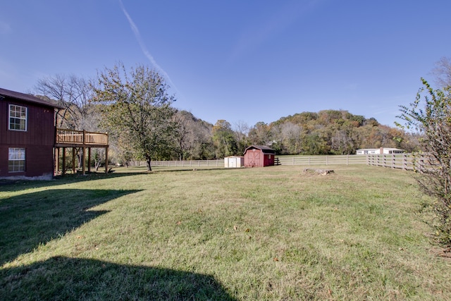 view of yard with a deck with mountain view, a storage unit, and a rural view