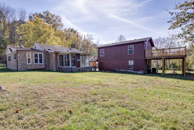 back of property with a wooden deck and a lawn