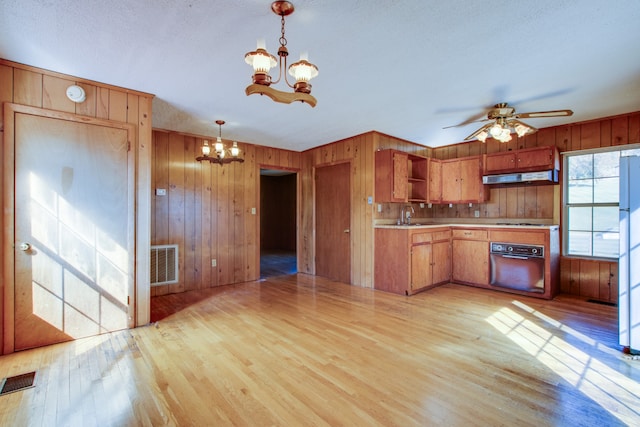 kitchen with wood walls, oven, sink, light hardwood / wood-style floors, and pendant lighting